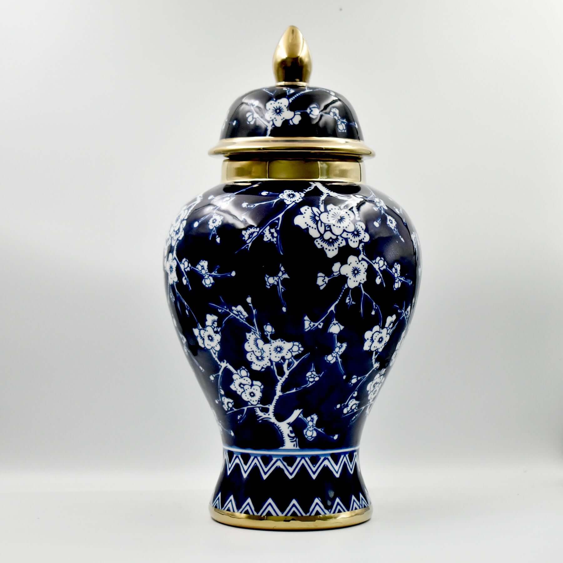Navy blue ceramic jar with white floral patterns and gold accents on a white background
