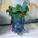 Glass vase with green and blue gradient on a marble surface