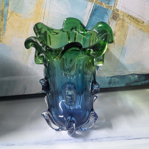 Glass vase with green and blue gradient on a marble surface