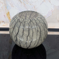 Spherical glass vase with textured surface against a abstract art background