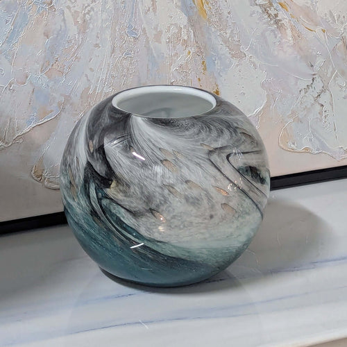 Glass vase with marbled design on a marble surface with abstract art in the background