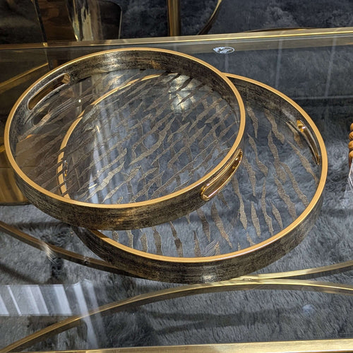 Vintage round serving tray with champagne gold details on a glass table, combines wood and sophisticated design for elegant serving.