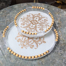 Elegant circular serving trays with decorative beading on a marble table, featuring intricate floral patterns and wood-plastic grips.