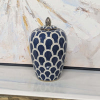 Blue and white patterned vase on a surface with abstract art in the background