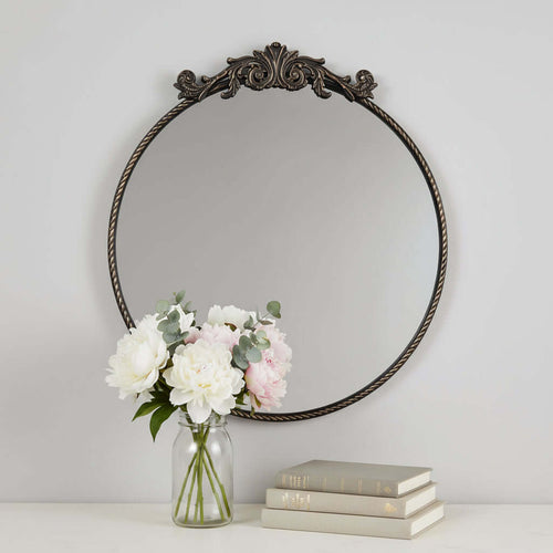 Round decorative mirror with ornate frame on a white background