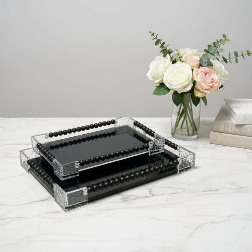 Set of black trays with decorative edges on a marble surface